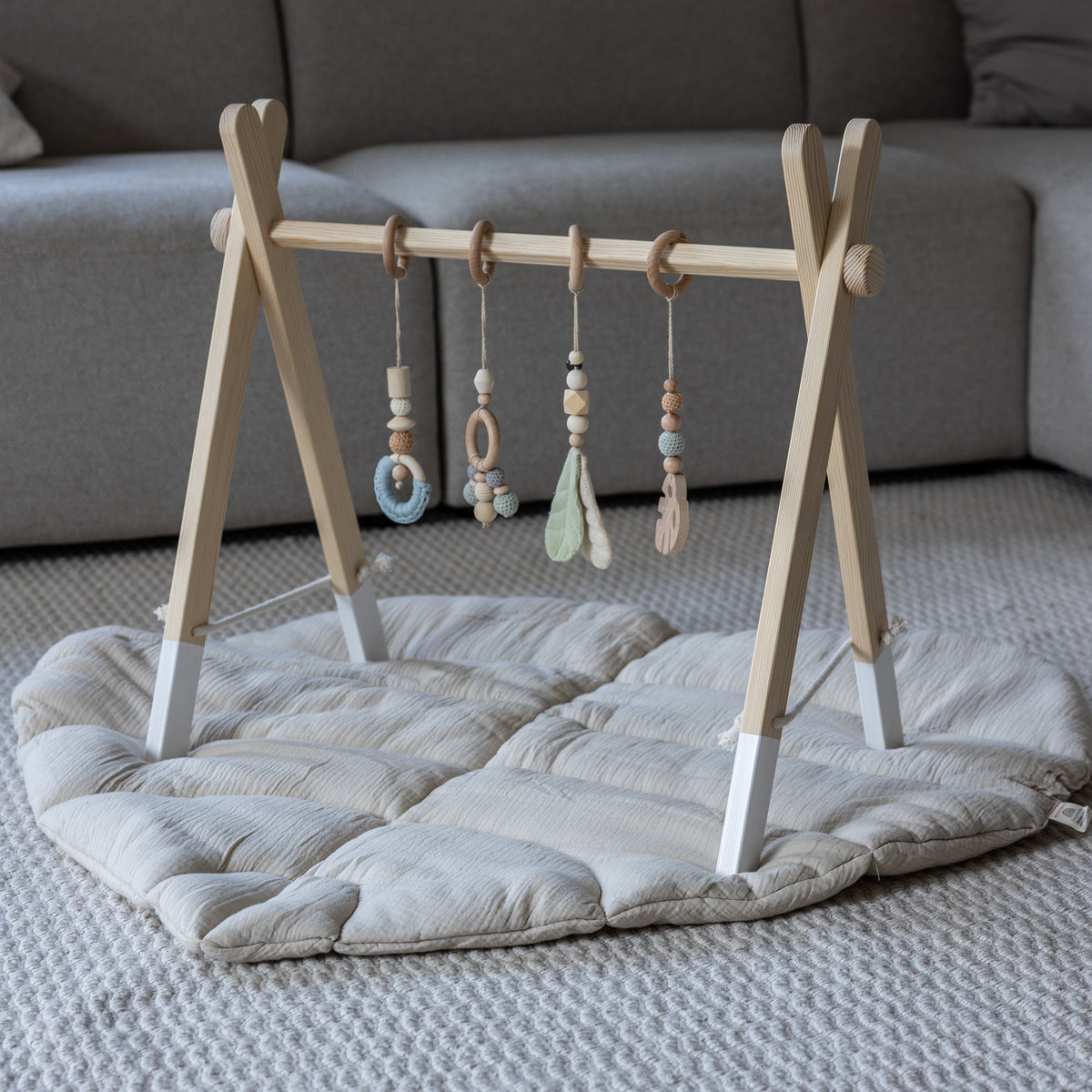 Klappbarer Spielbogen aus Holz mit weißen Füßen vor dem Sofa