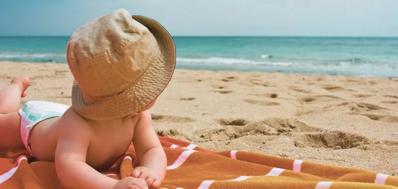 Baby am Strand mit Sonnenhut