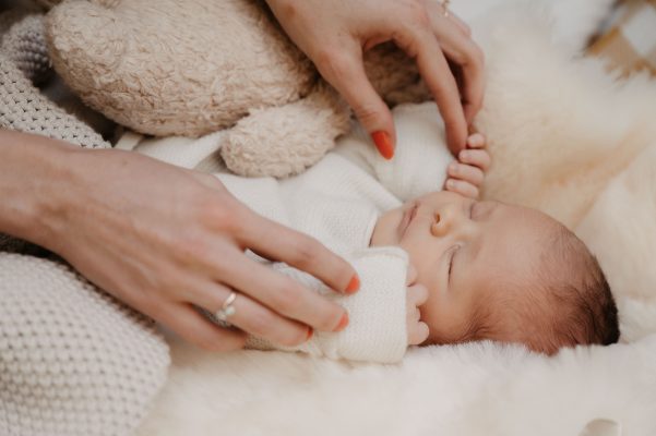 Baby schläft währen die Mama es sanft mit den Händen berührt